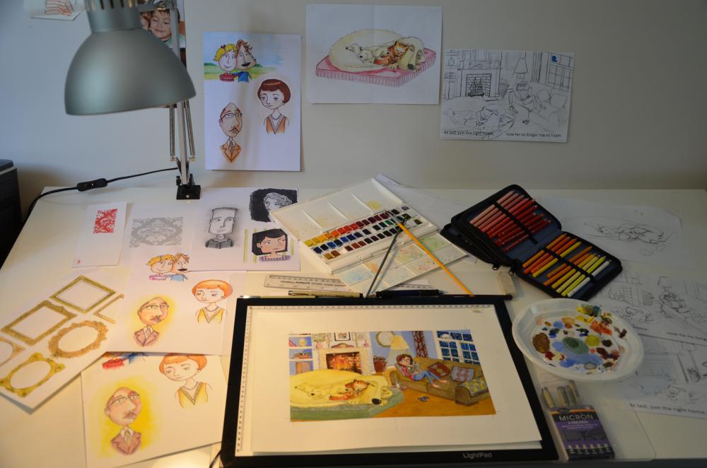 Simple beginner art kit with sketchbook, graphite pencils and coloured pencils laid out on a desk